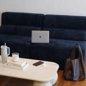 Navy blue sofa with a laptop, coffee cup, and phone on a wooden coffee table.