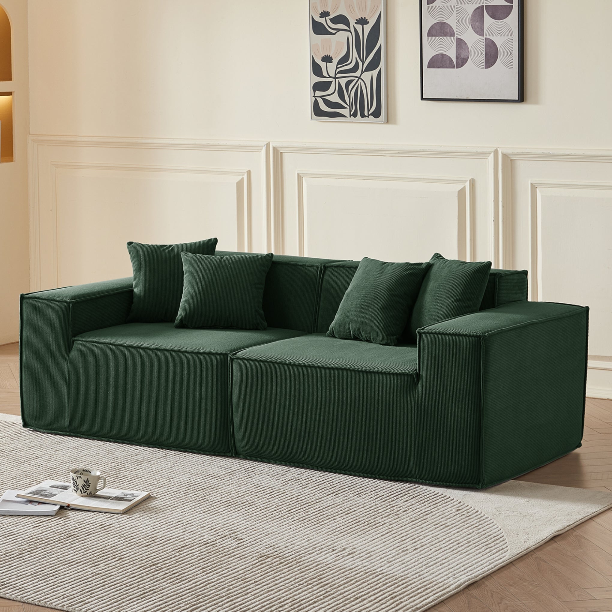 Green sofa in a living room with decorative pillows and framed art on the wall.