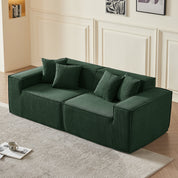 Green sofa in a living room setting with a rug and coffee table.
